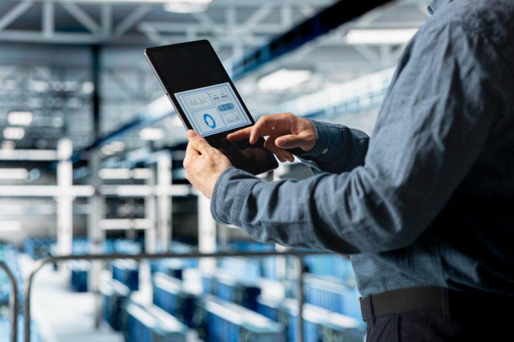 Warehouse professional using a tablet to monitor temperature and performance data in a cold chain logistics facility.