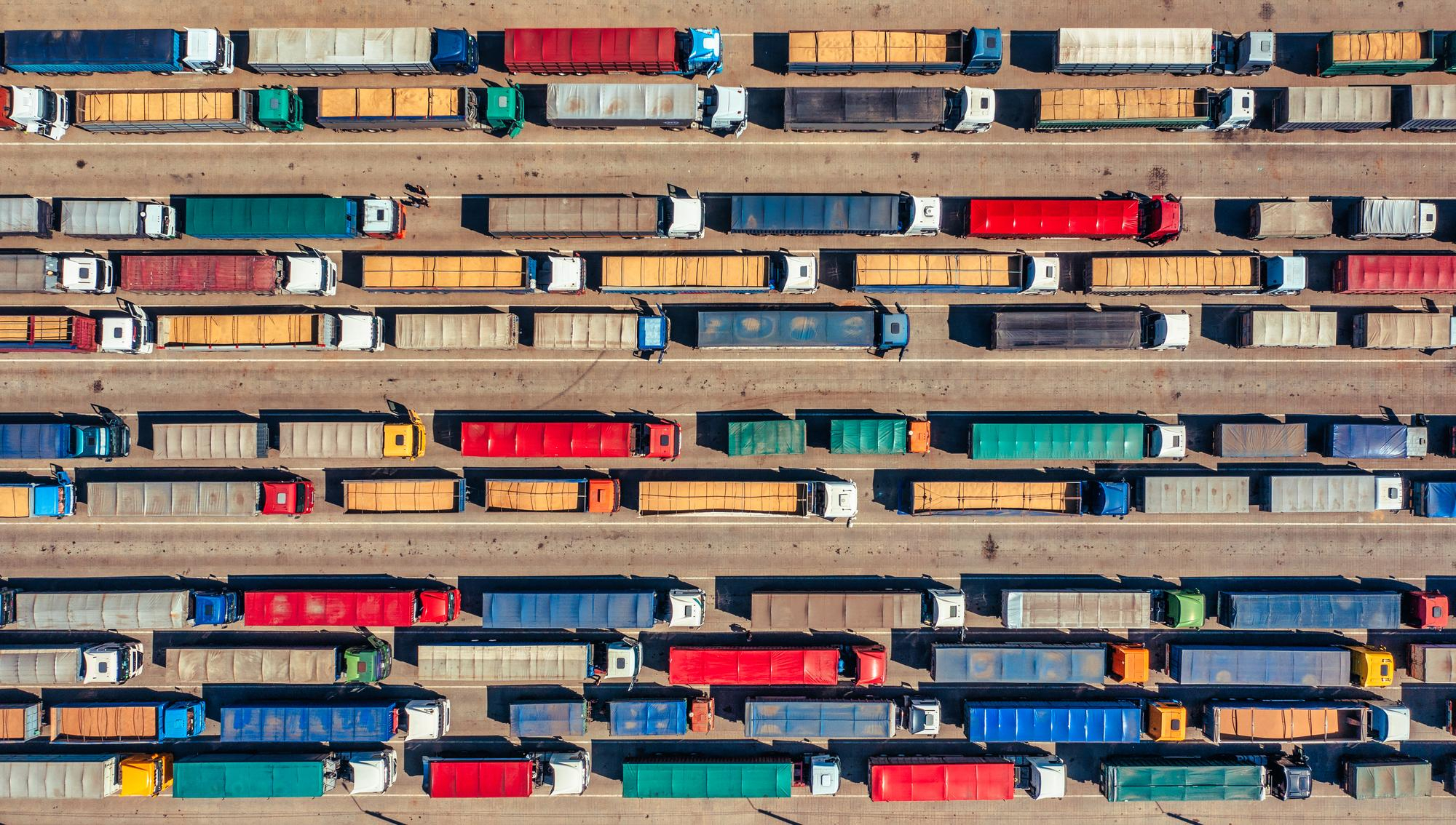 Container trucks waiting in line at a busy port terminal, representing drayage delays and supply chain congestion.